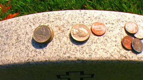 What do coins on military tombstones mean?
