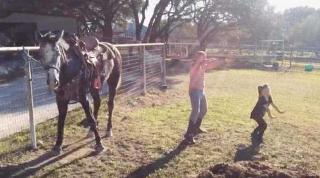 Two little girls spotted dancing next to the horses