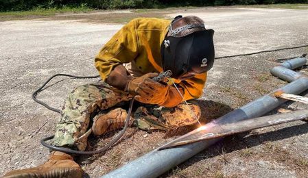 A sailor uses shielded metal arc welding to repair a pipe at Naval Base Guam,